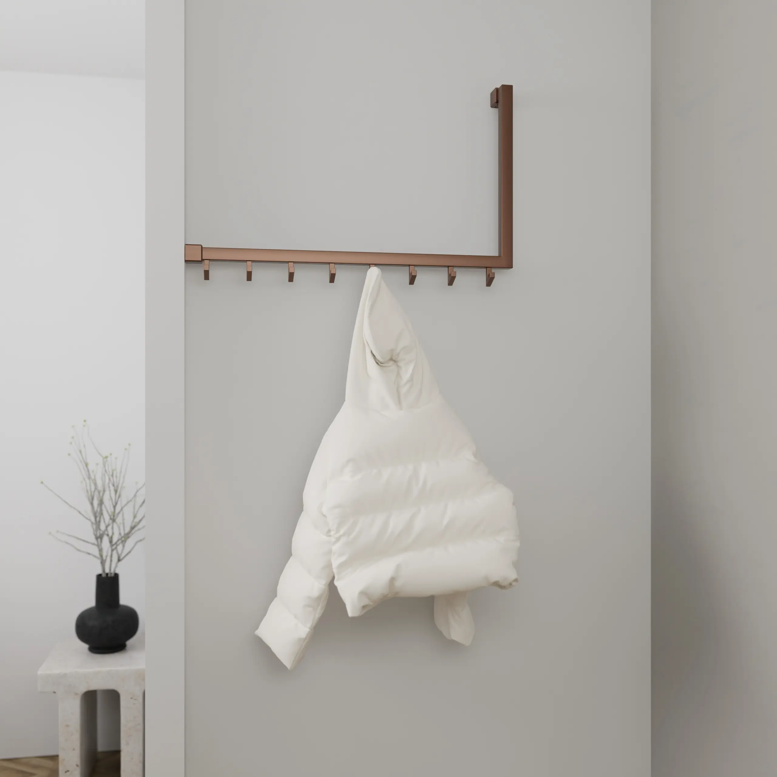 Wandkapstok Lune vierkant brons in een hoekopstelling aan de wand gemonteerd met kleding.