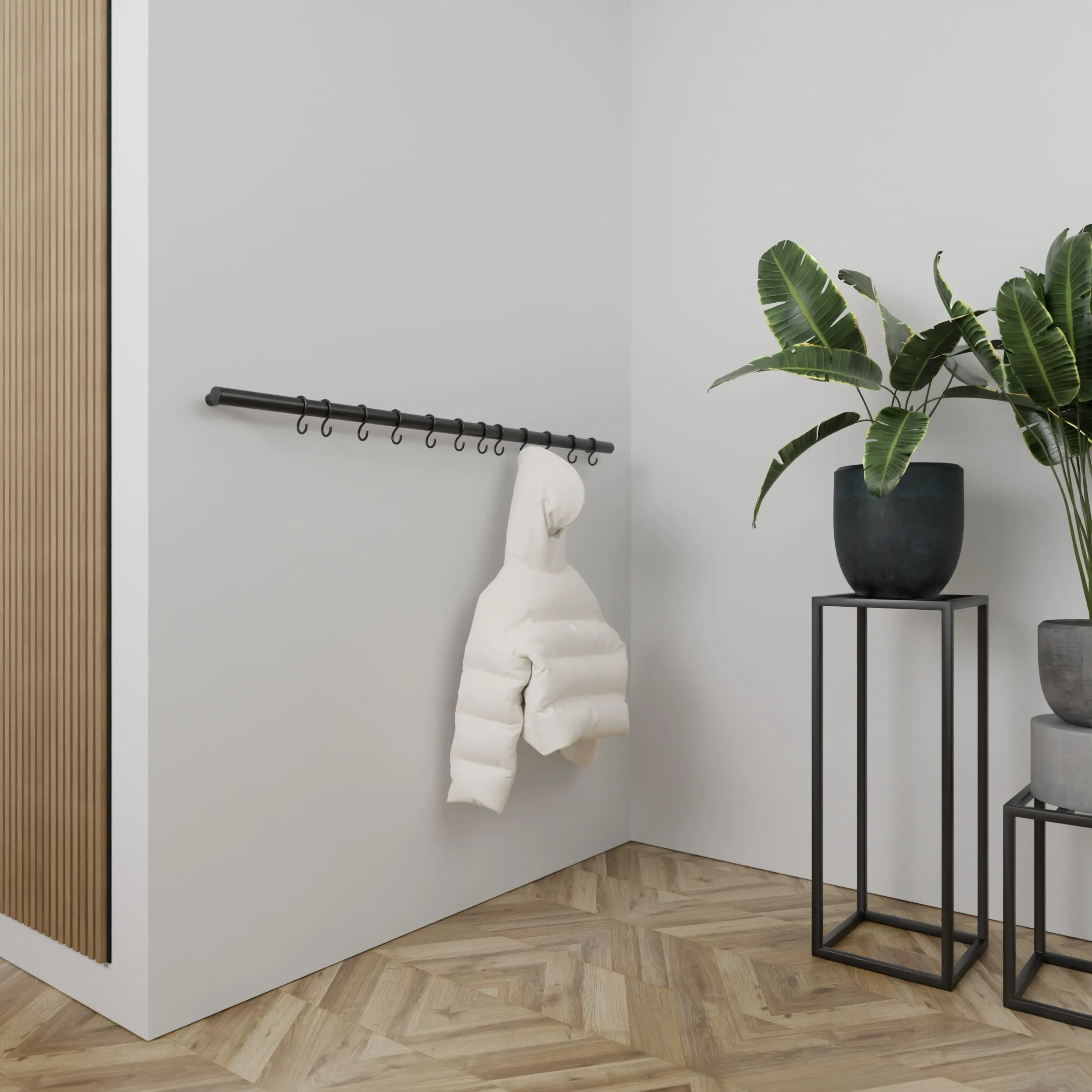 Wandkapstok Hylan rond zwart aan de wand gemonteerd in een interieur met kleding.