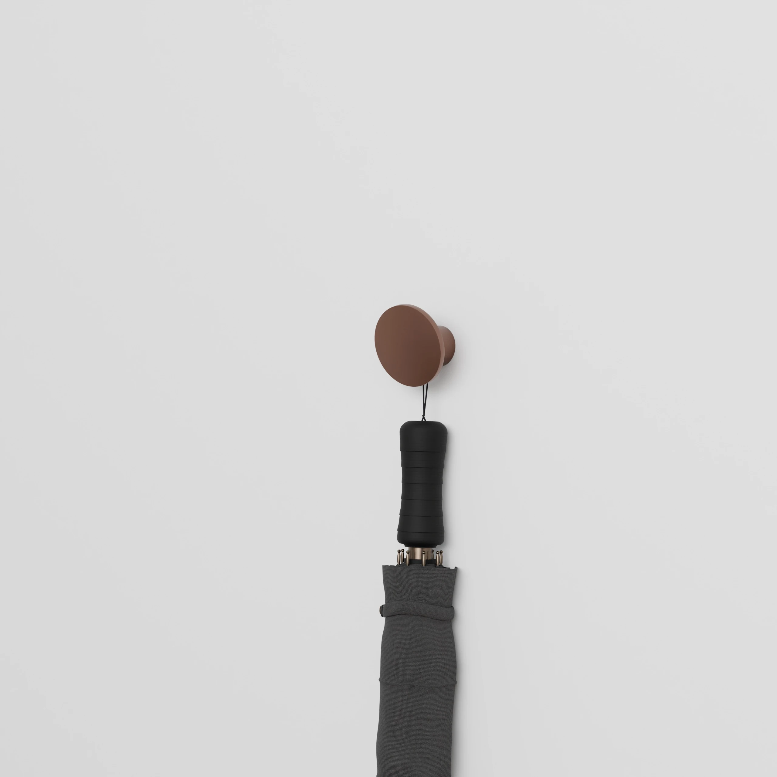 Wandkapstok Halo rond brons aan de wand gemonteerd met een paraplu eraan.