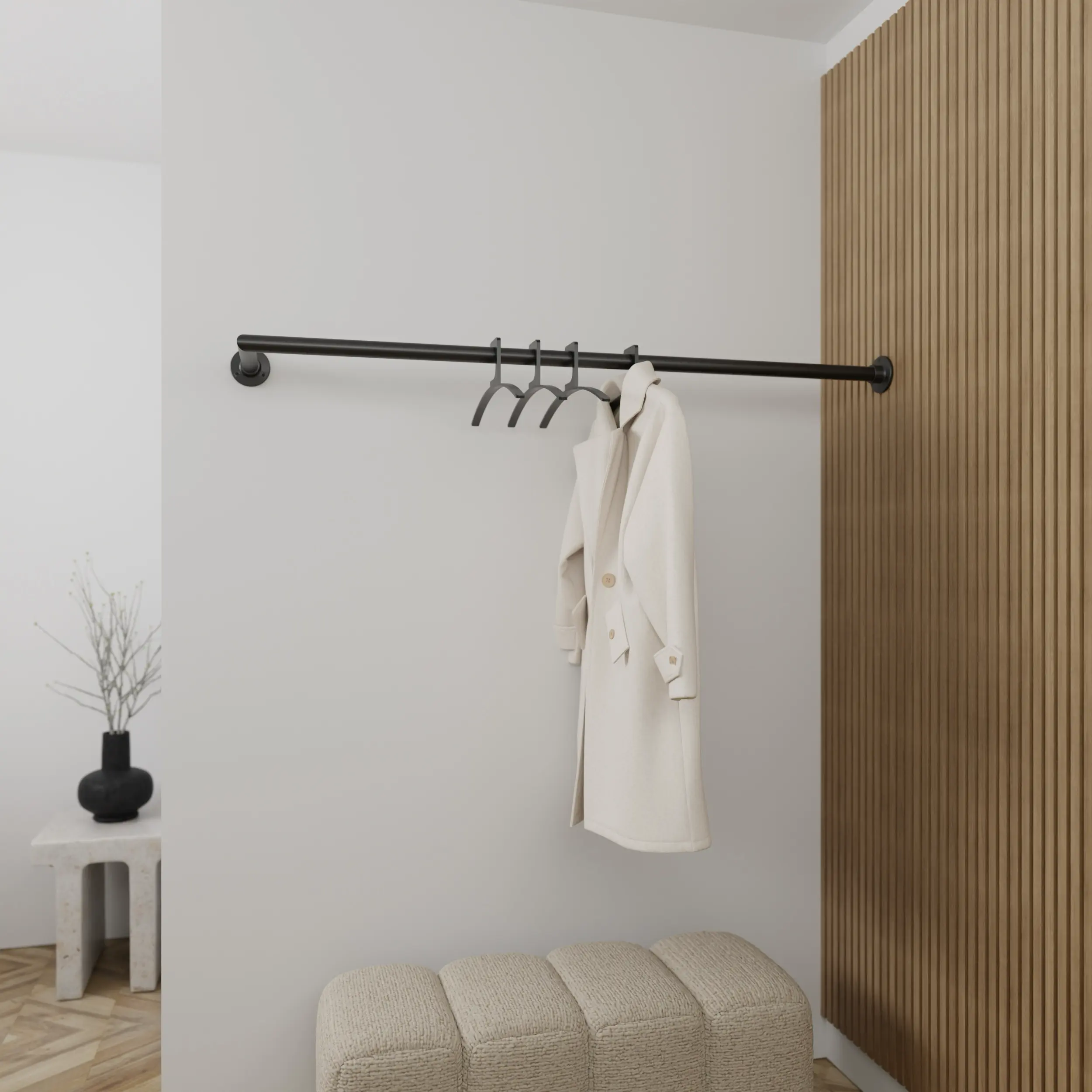 Wandkapstok Lauvem rond zwart aan de wand gemonteerd in een interieur met kleding.