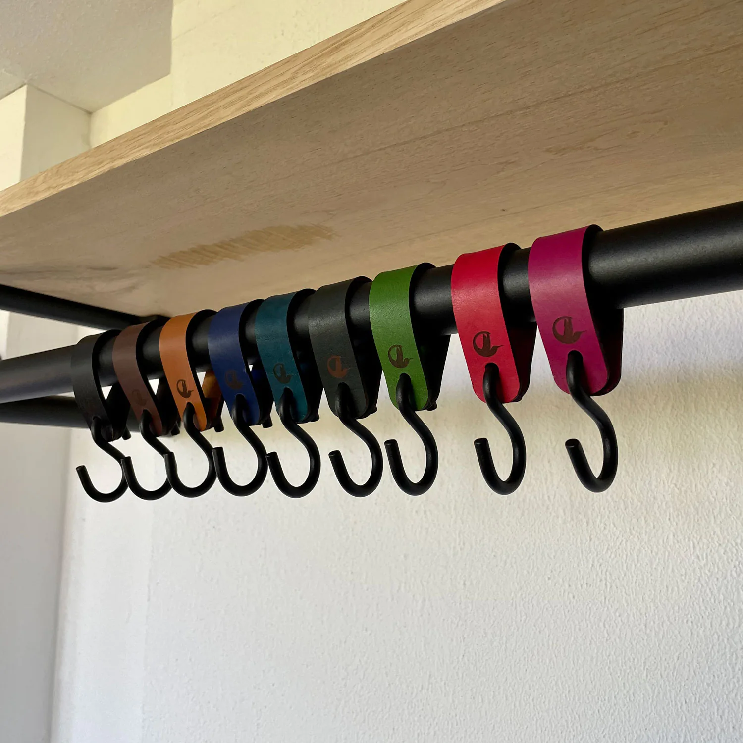 Haak Lero wit in een interieur met meerdere gekleurde haken aan een stang.