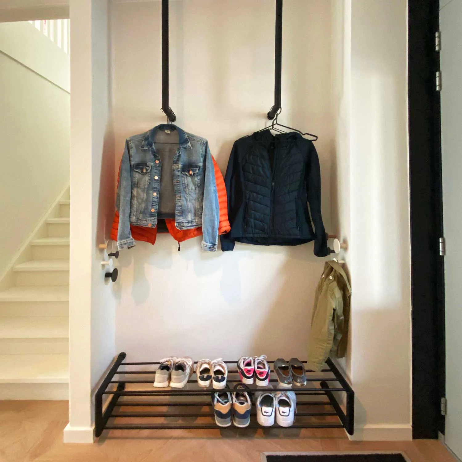 Schoenenrek Norin rond zwart in een hal geplaatst met schoenen op het rek.