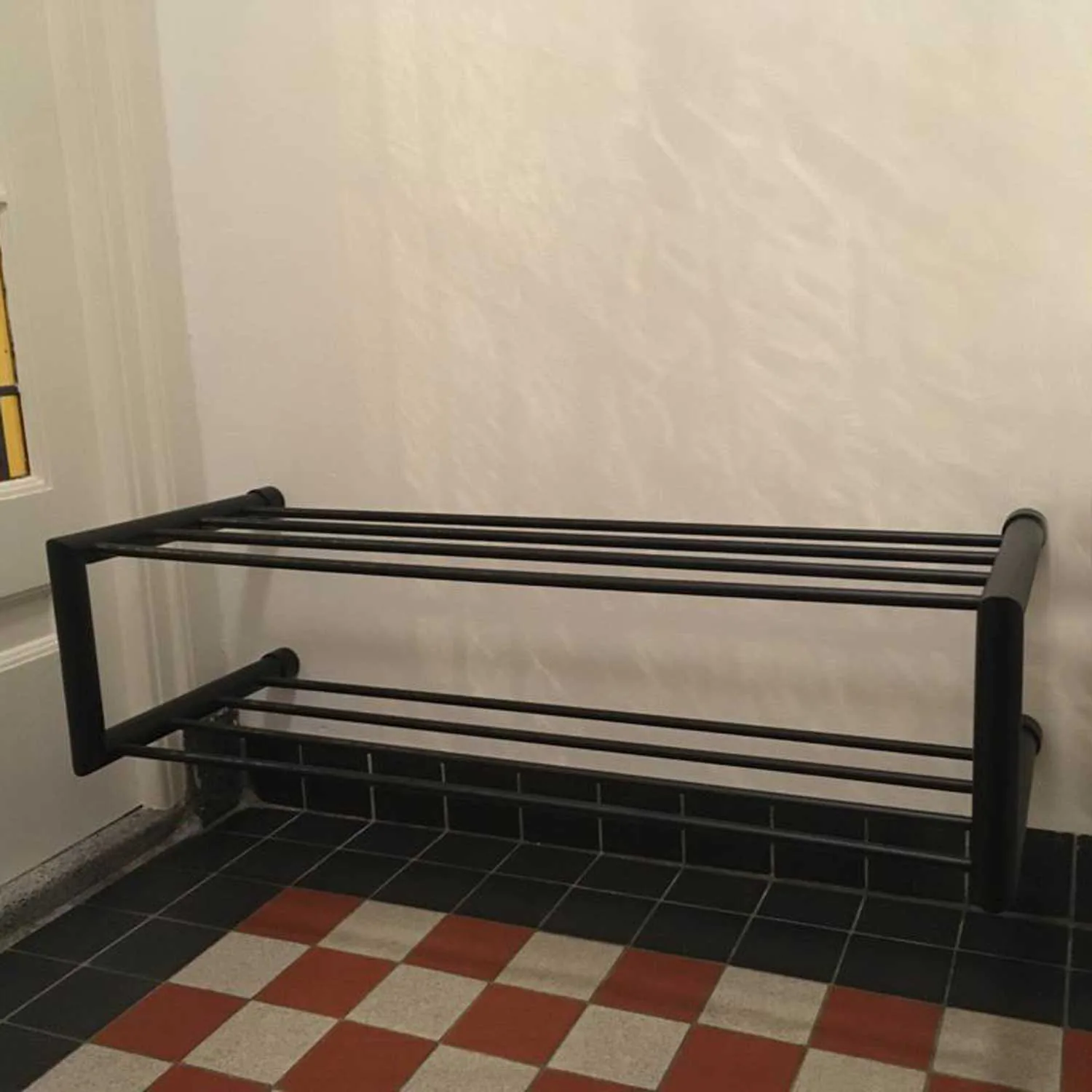 Schoenenrek Norin rond zwart in een interieur geplaatst met schoenen op het rek.
