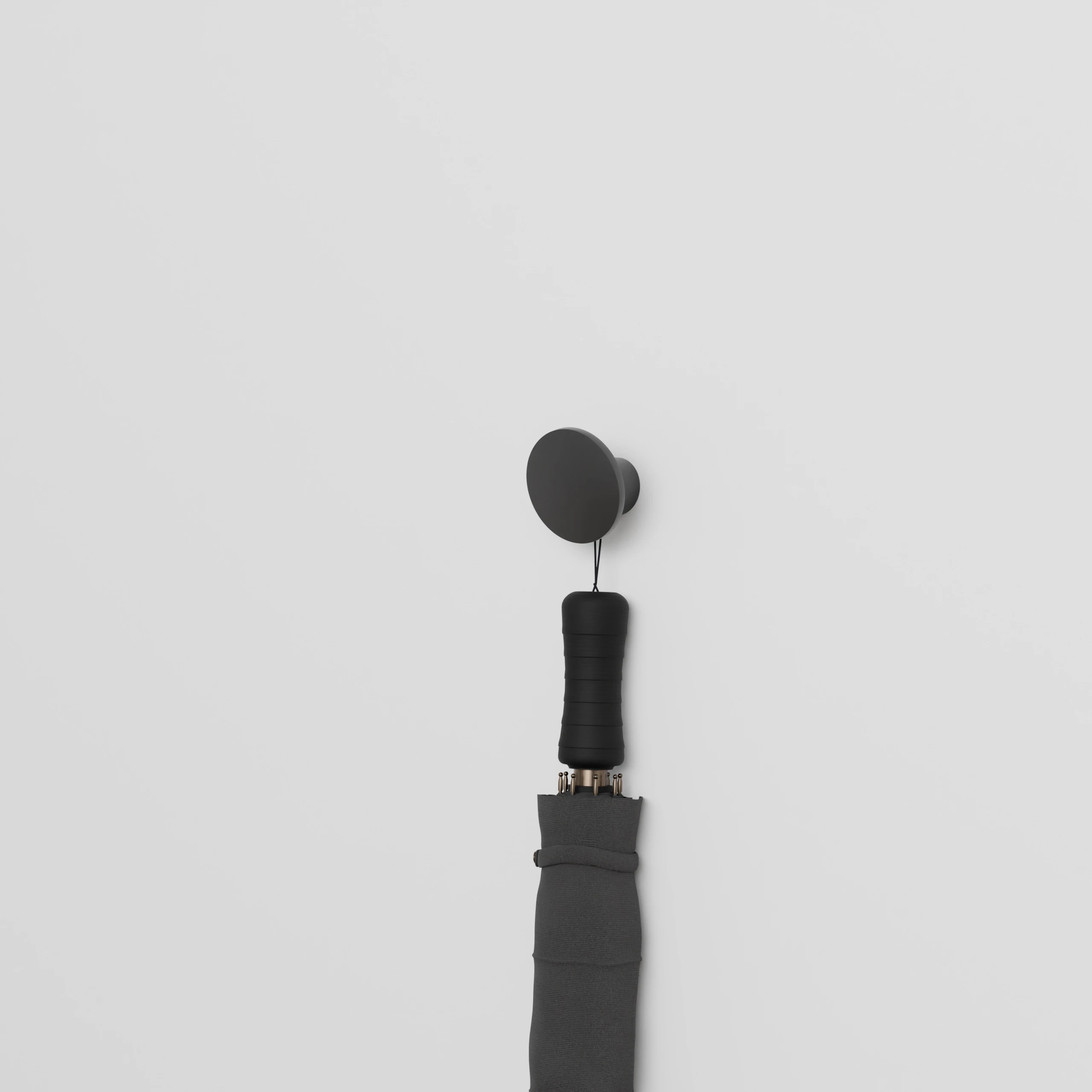 Hook Halo round black mounted on the wall with an umbrella hanging from it.